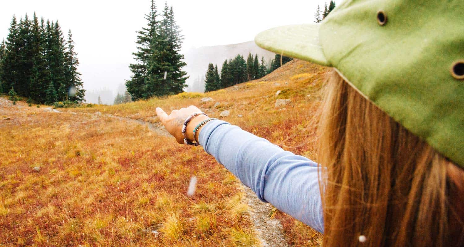 girl hiker in green hat pointing direction along mountain trail easy beginner hikes near denver