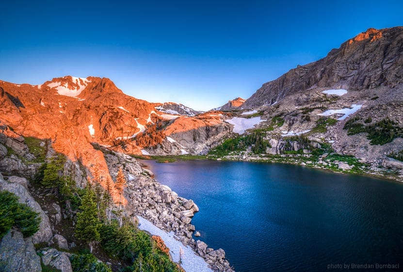 Wild Basin in Rocky Mountain National Park sunrise on rock of deep blue lake on hike near denver colorado