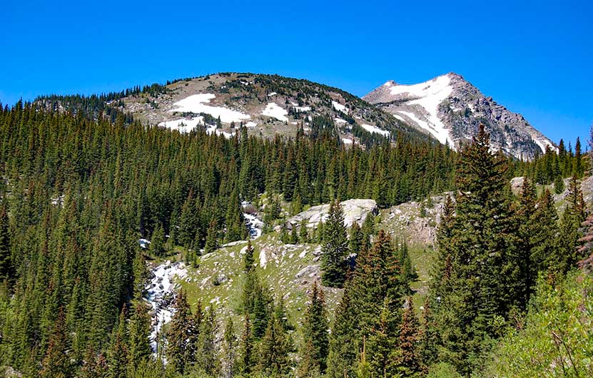 mountain peaks with late summer snow and cascading creek through high mountain meadow in indian peaks wilderness near jasper lake and devils thumb lake