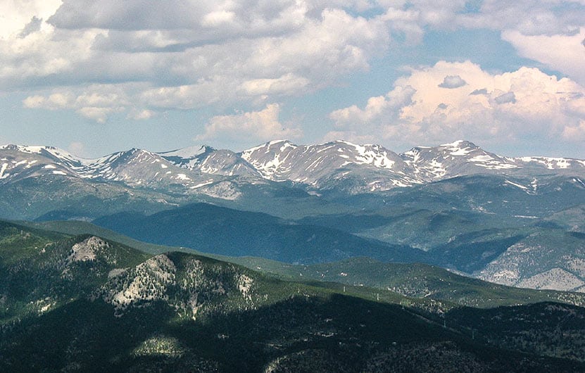 green mountains in front of snowcapped mount evans panoramic view with clouds from an top of chief mountain colorado