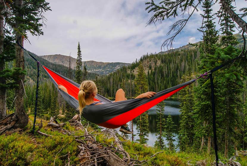 woman in hammock overlooking mountain lake with mountains in background hikes near denver